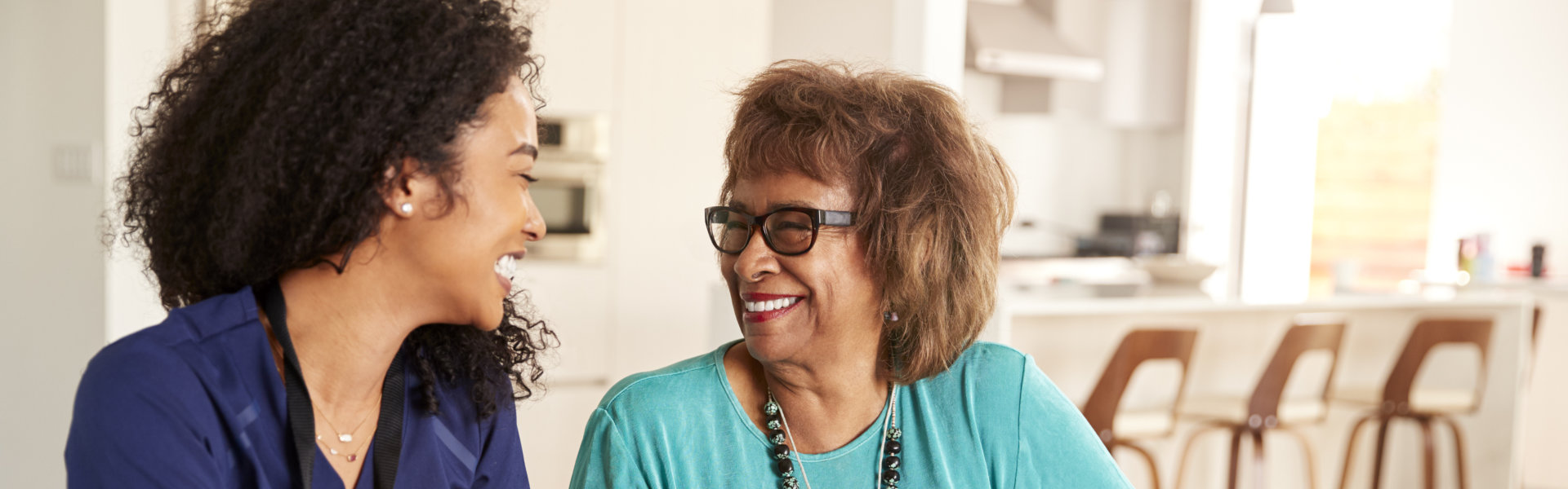 aide and elderly woman smiling at each other